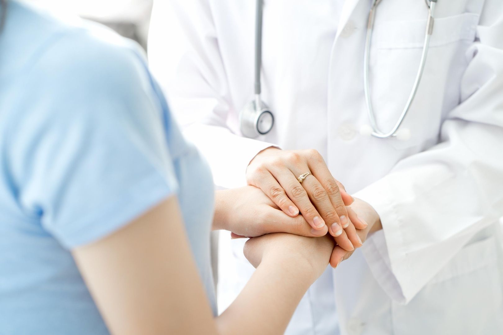 Ein Arzt hält die Hand eines Patienten und bietet ihm Trost und Unterstützung während der Behandlung.