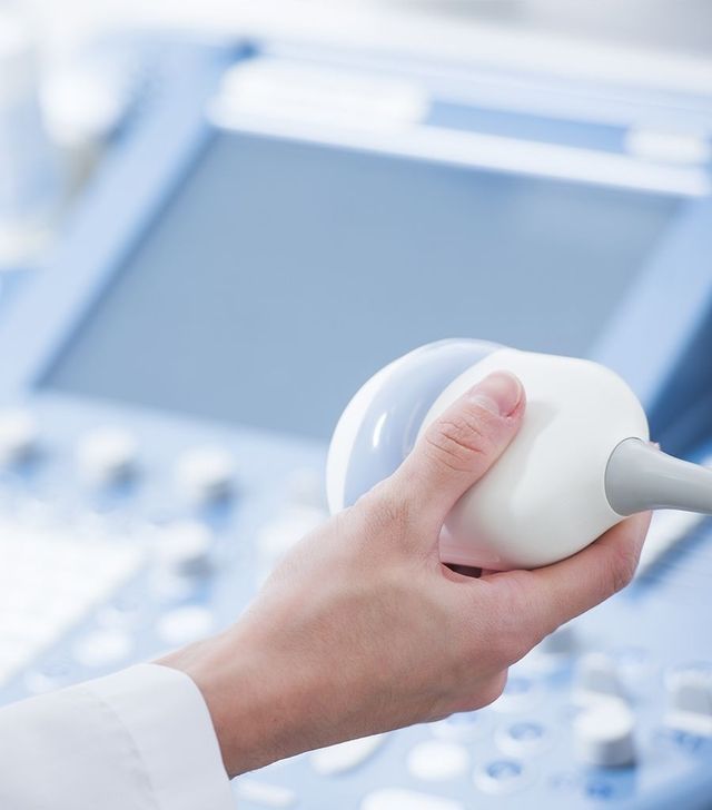 Eine Person hält ein Ultraschallgerät vor einem Computer.